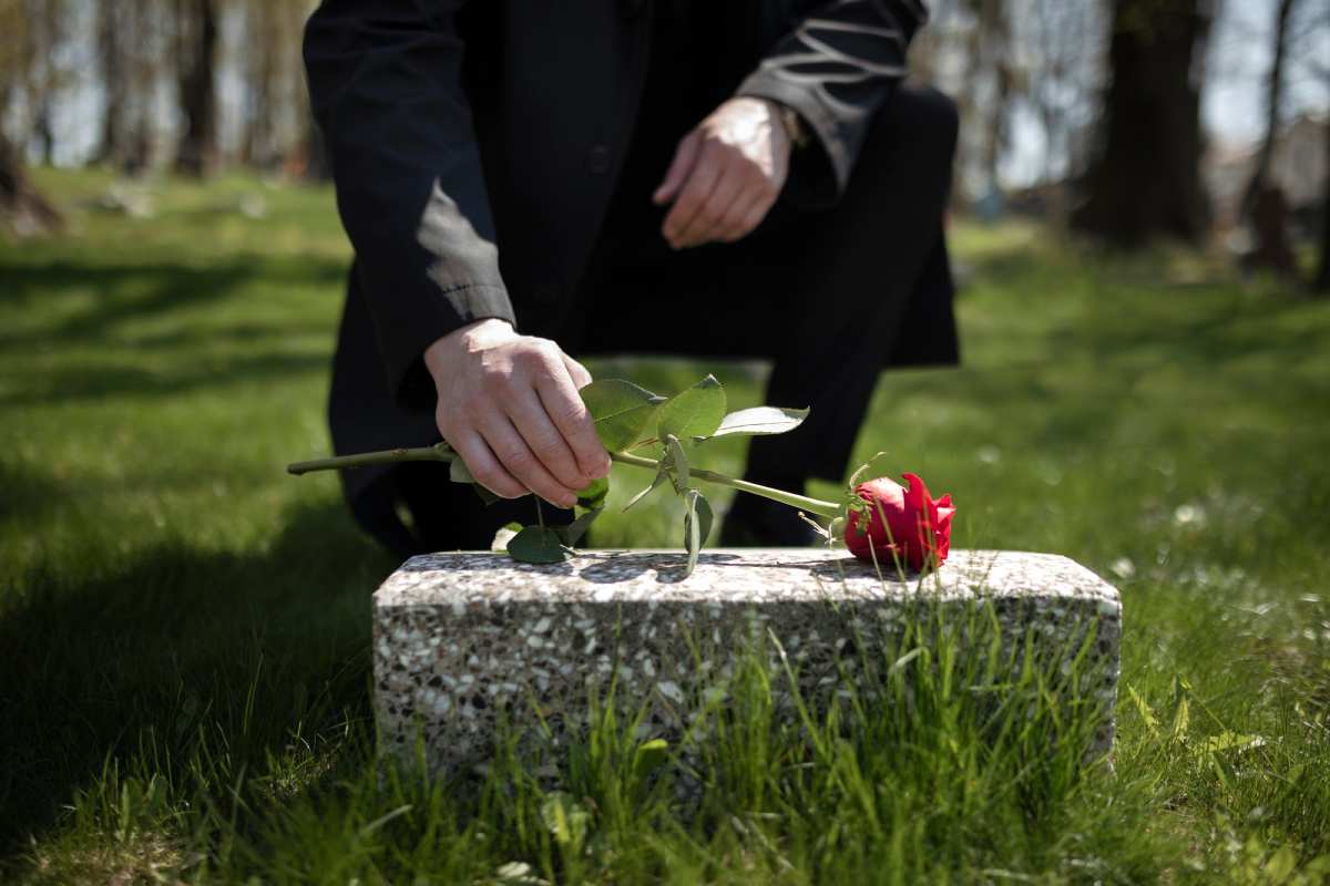 man-bringing-rose-tombstone-cemetery