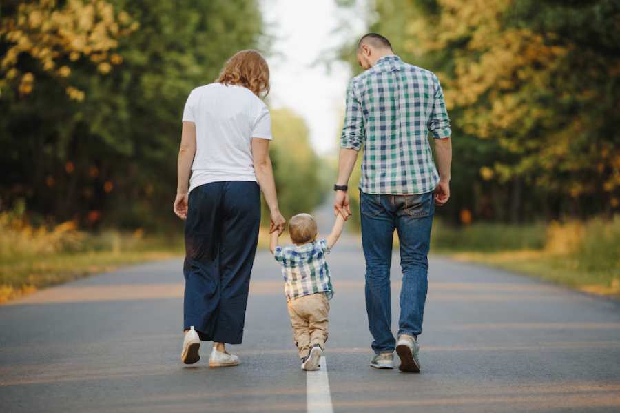 parents-holding-their-little-son-are-walking-road parents-holding-their-little-son-are-walking-road